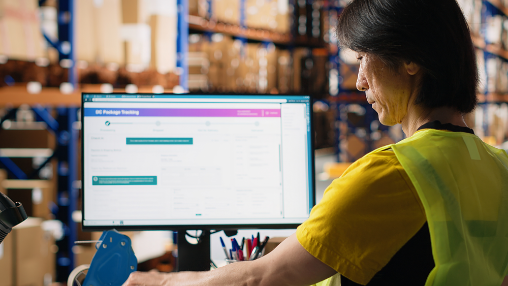 asian-employee-typing-tracking-info-from-airway-bill-labels-before-shipping-parcels-managing